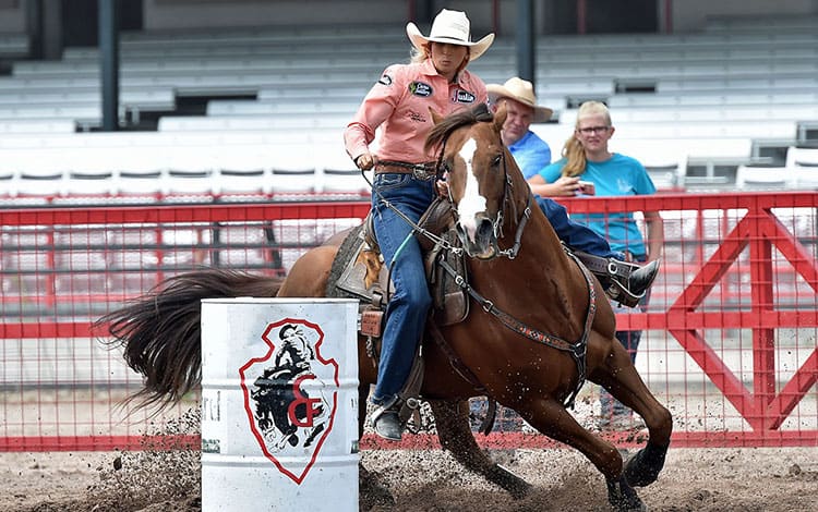 Women rides horse around barrel